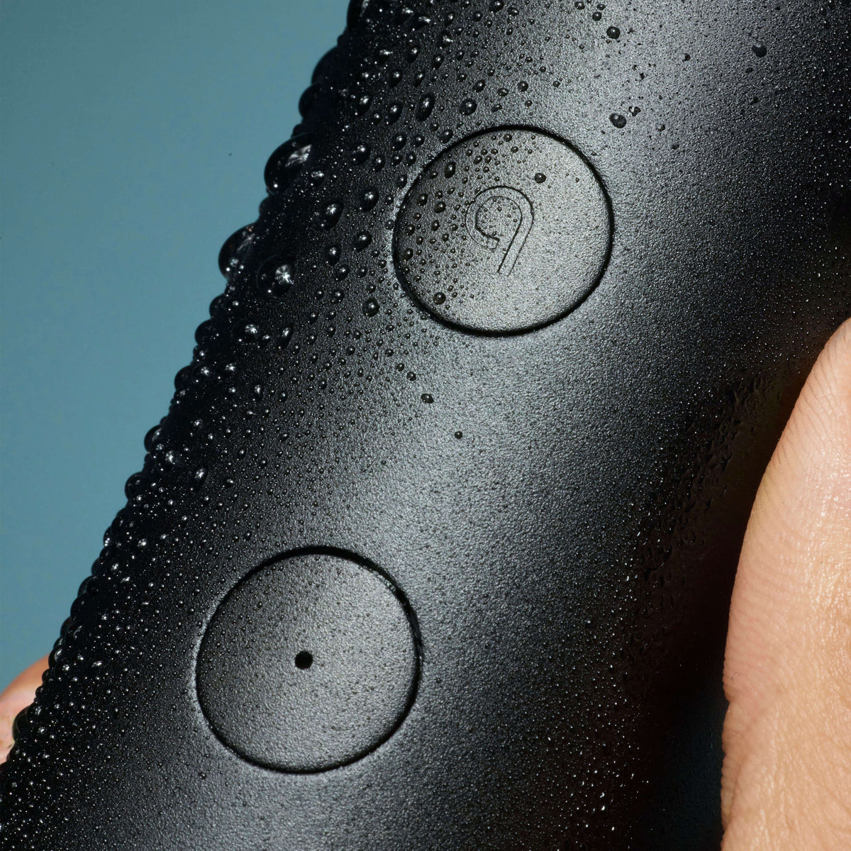 Black electronic device with water droplets on a blue background