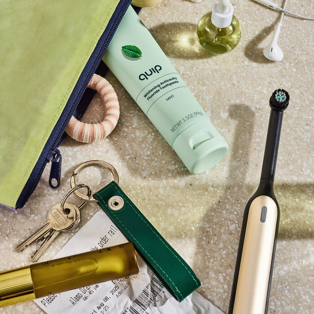 Quip electric toothbrush, keychain, and other items on a textured surface