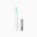 An image showing a white electric toothbrush head refill with soft bristles and a tongue scraper, accompanied by a AAA battery.