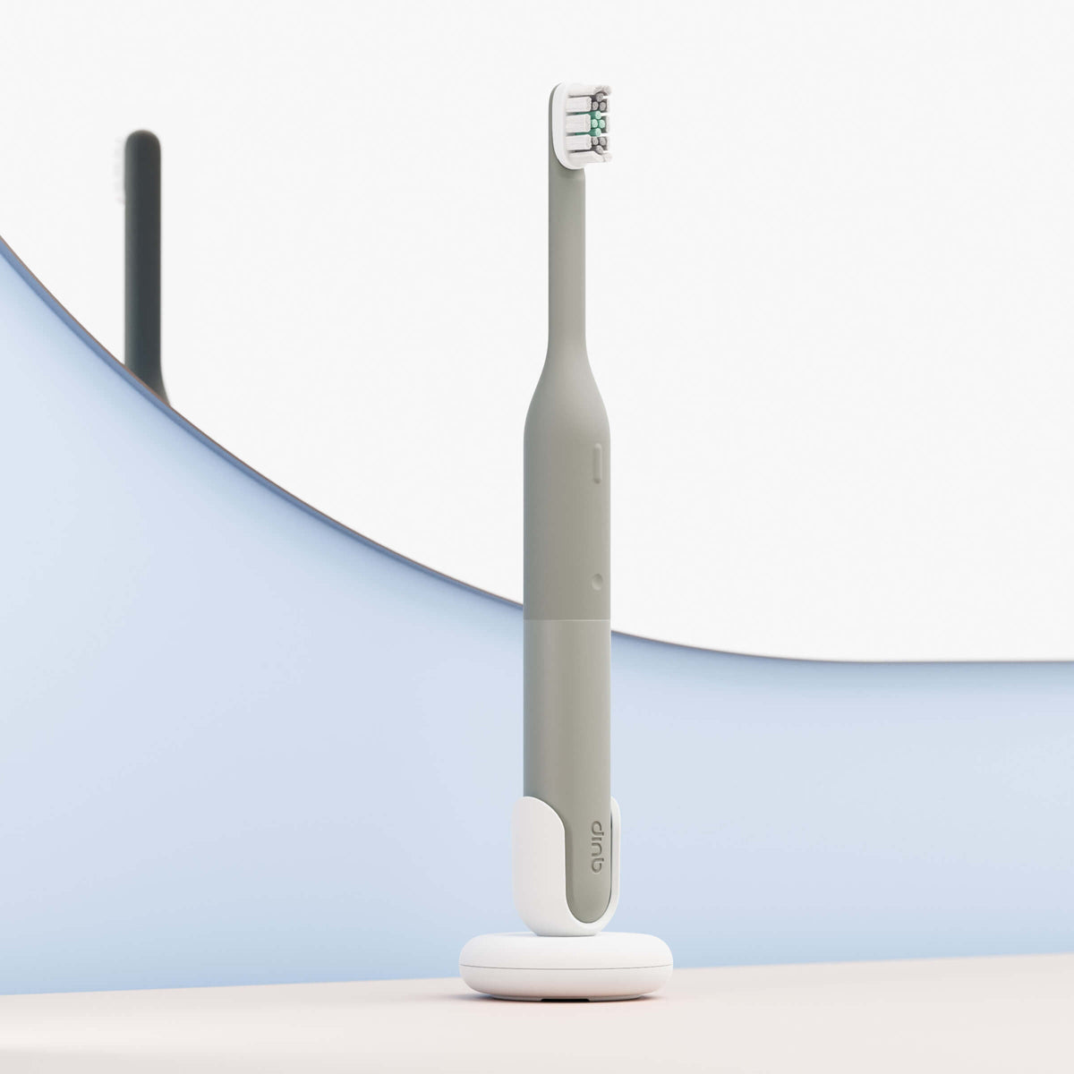 Gray electric toothbrush on a white stand with a blurred background